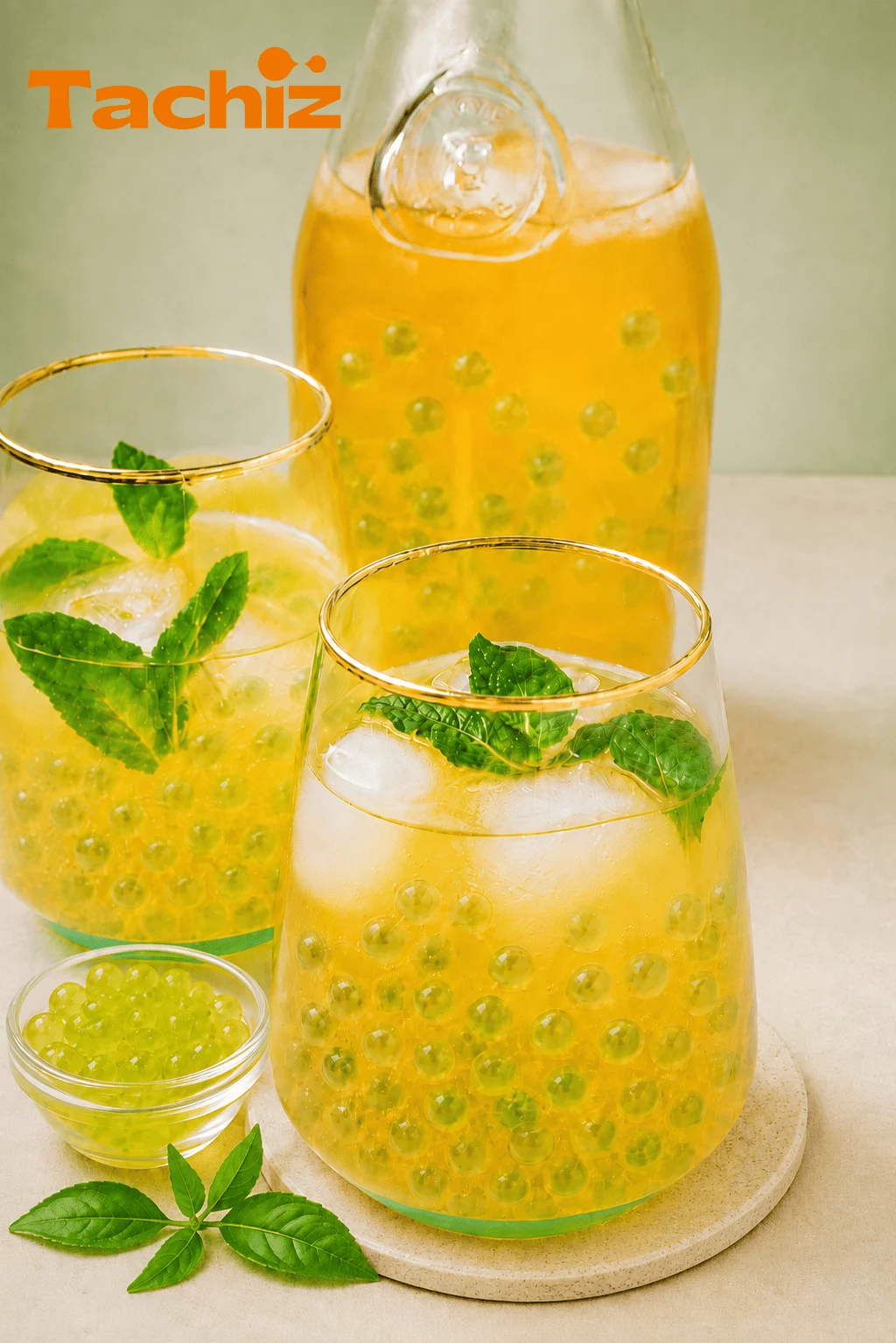 A refreshing glass of cold brew iced tea featuring Tachiz mango popping boba, garnished with fresh mint leaves for a summer drink menu.